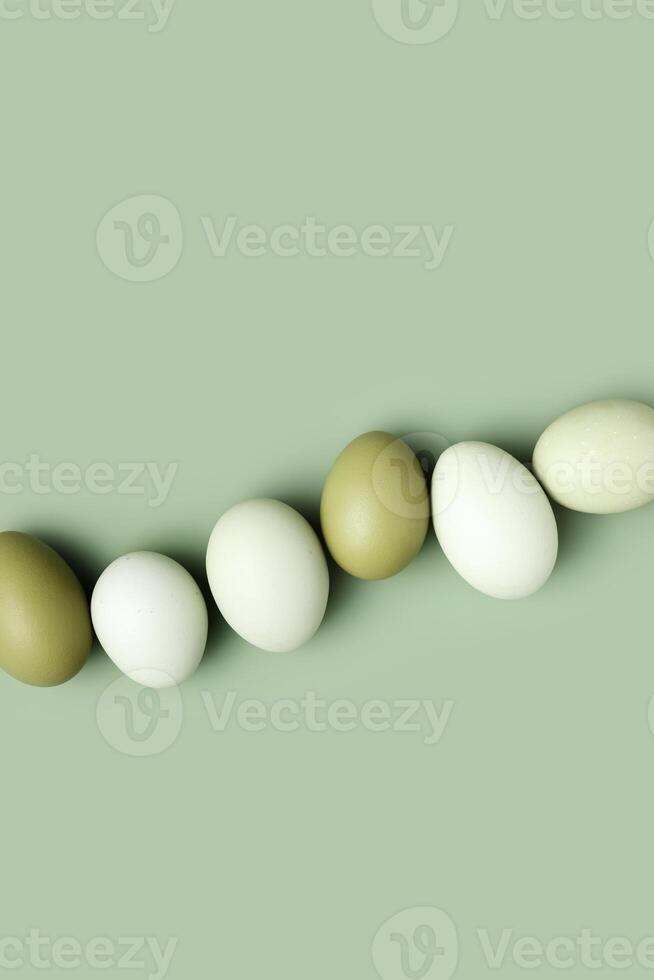 Natural green white colored chicken Eggs with sun shadows, minimal style aesthetic holiday background, organic dyed eggs for easter celebration, minimalist food composition, pastel color, copy space photo