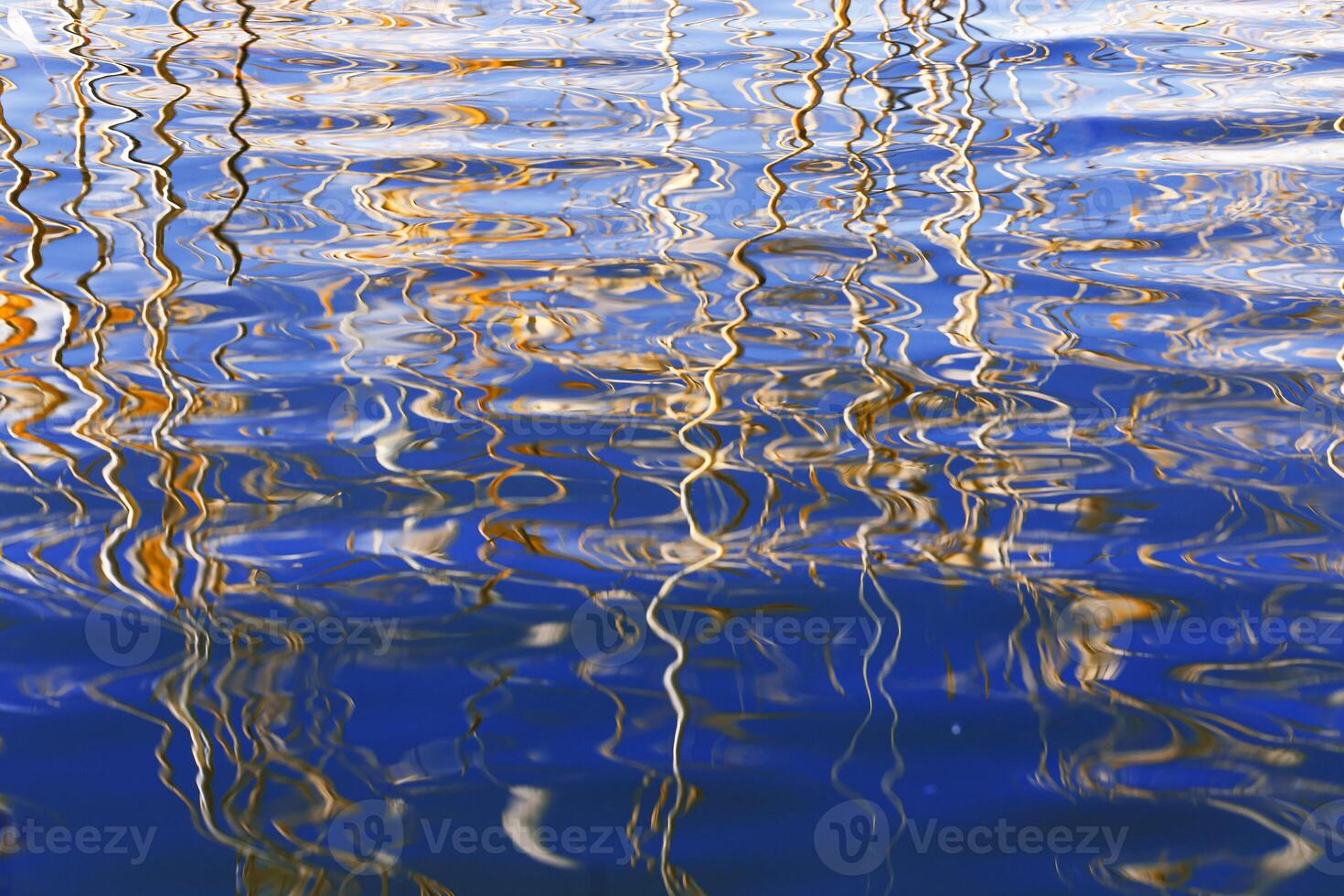 Dry reeds and their water reflections, nature landscape yellow blue vivid colors. Growing grass or plants in lake or wetlands, abstract natural background of reflects curved lines on water photo