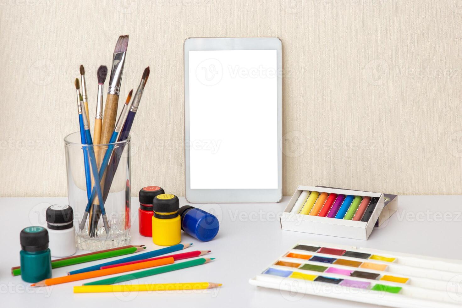 table with digital tablet on table with colorful drawing supplies photo