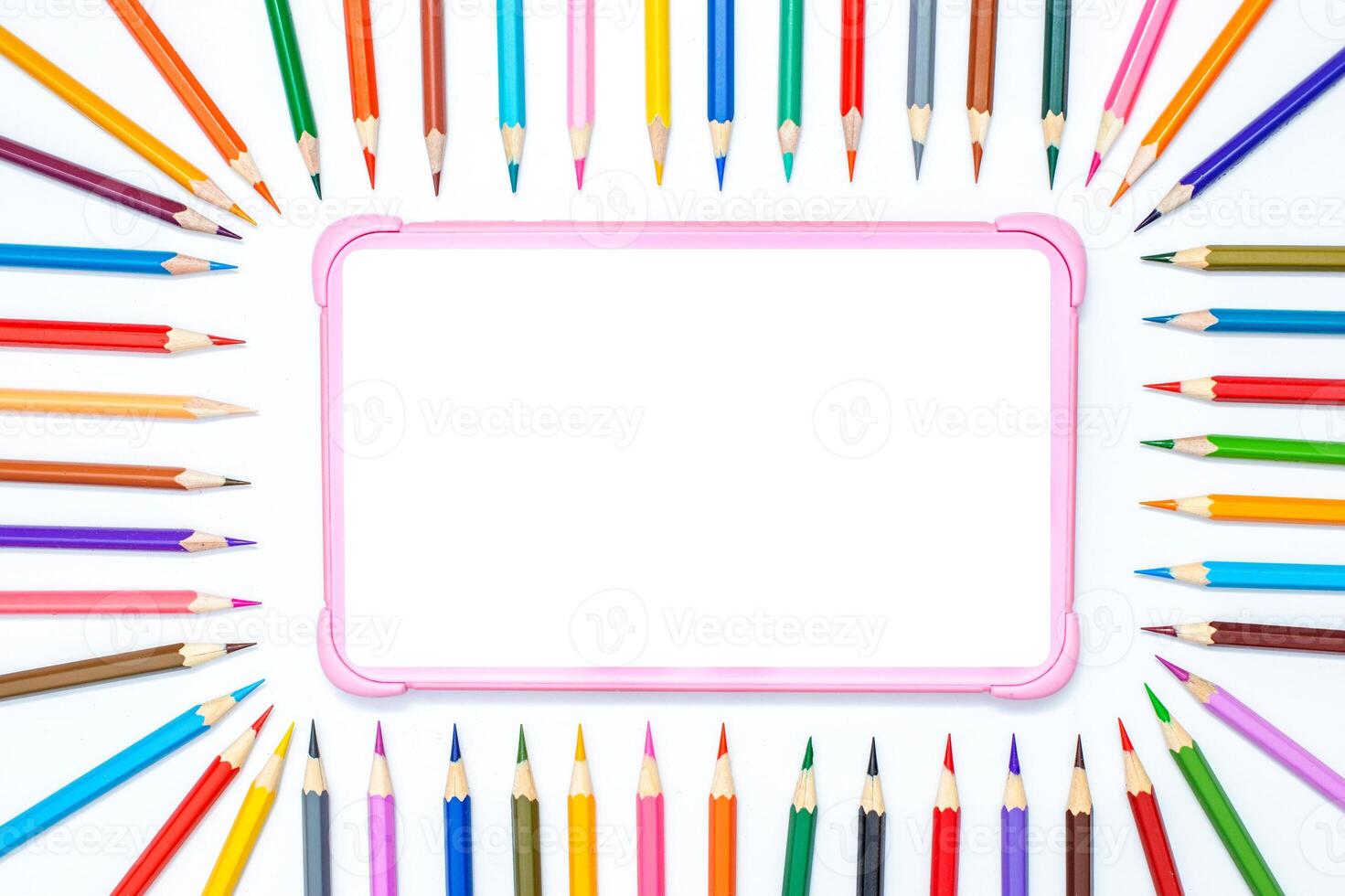 digital tablet on a white table with a frame of colored pencils photo