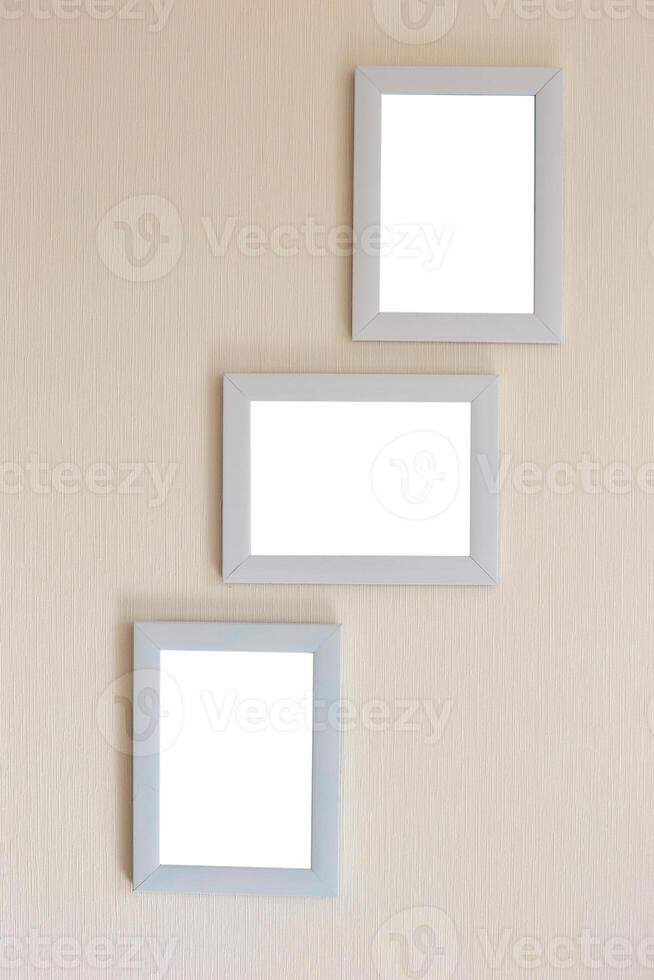 Collage of three white frames on a beige wall photo
