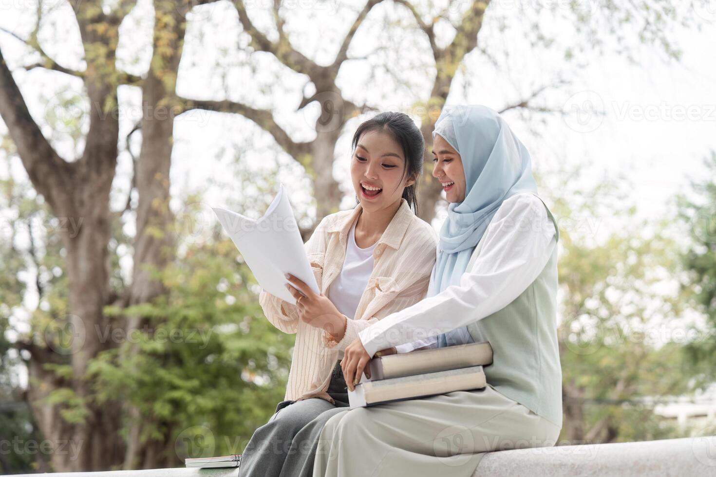 Diverse female students excitedly discussing study materials in a university park. photo