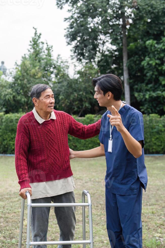 Supportive caregiver sharing a moment with elderly man using walker, fostering connection and well-being in a vibrant garden photo