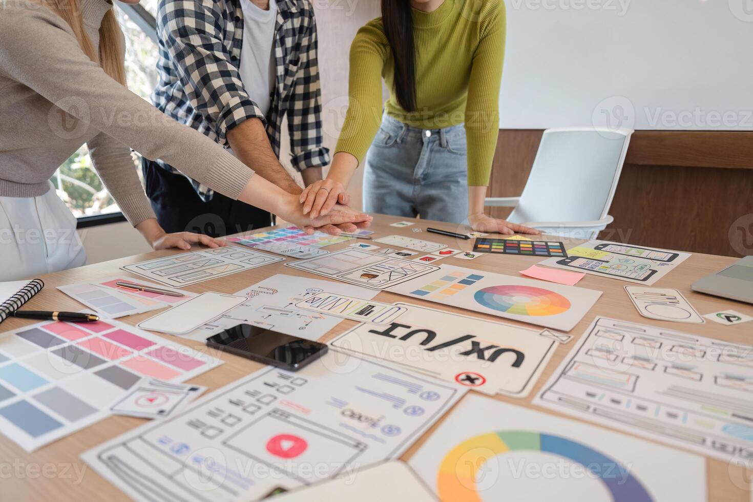 Diverse team collaborating on UX design project, celebrating creativity and teamwork at a modern workspace. photo