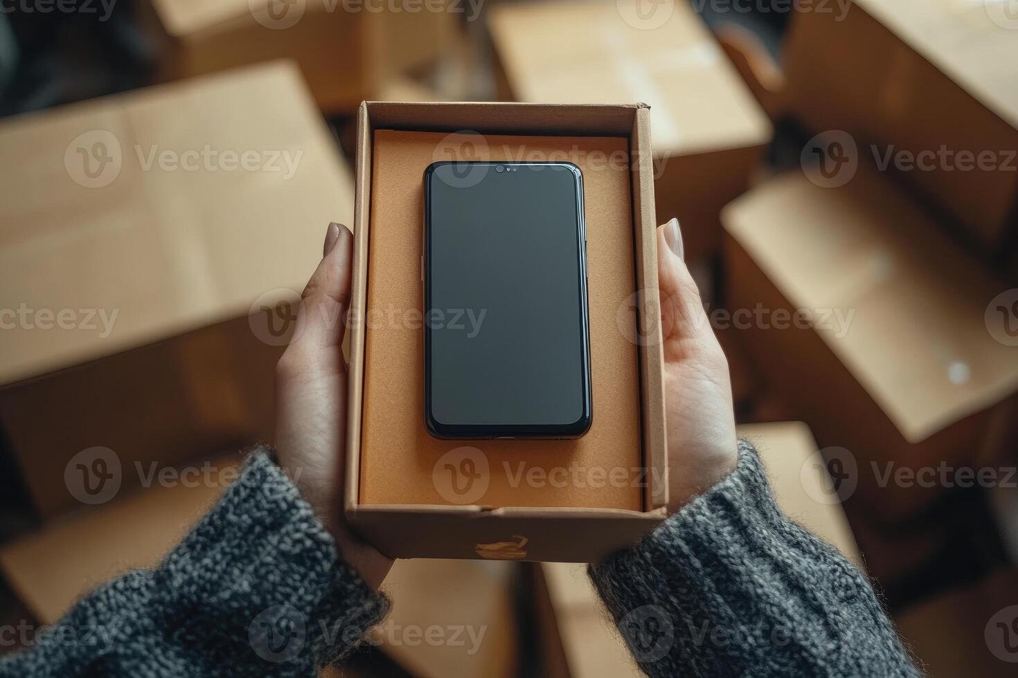 Warehouse worker holding new smartphone in a box, surrounded by cardboard boxes photo