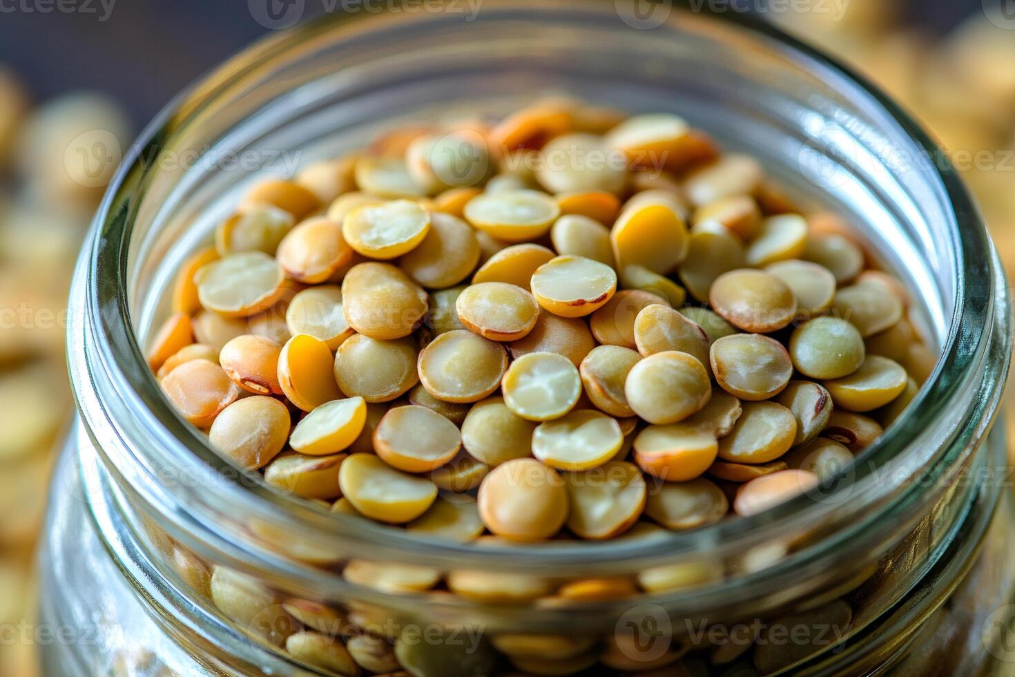 Yellow lentils filling glass jar on wooden table photo
