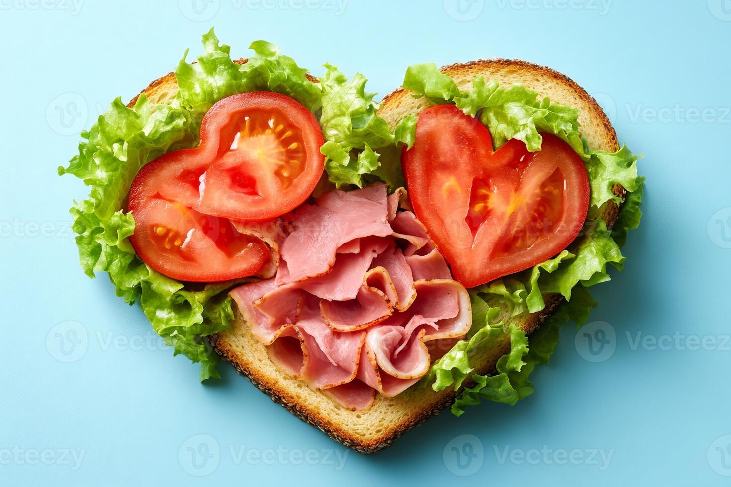 Heart shaped sandwich with ham, lettuce and tomato on blue background photo