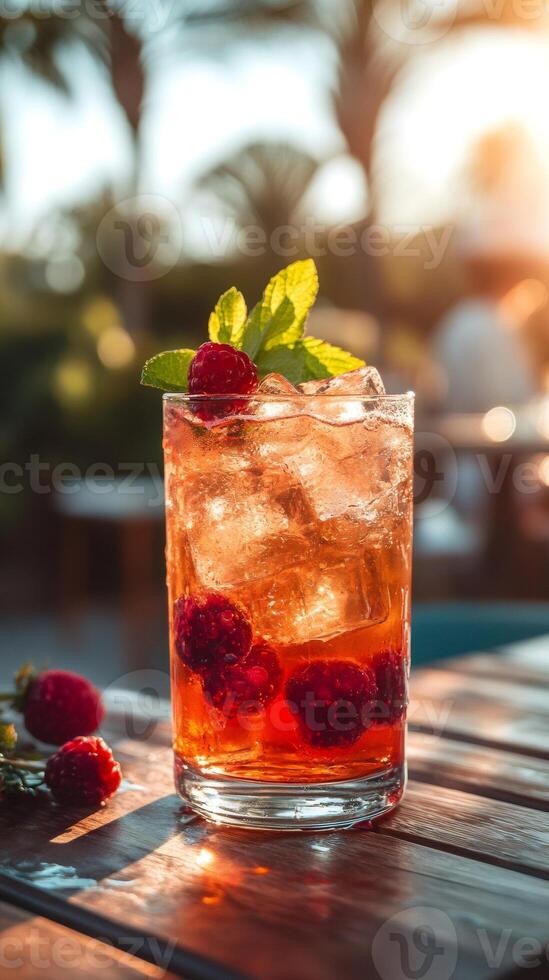 Refreshing raspberry cocktail garnished with mint on wooden table at sunset photo
