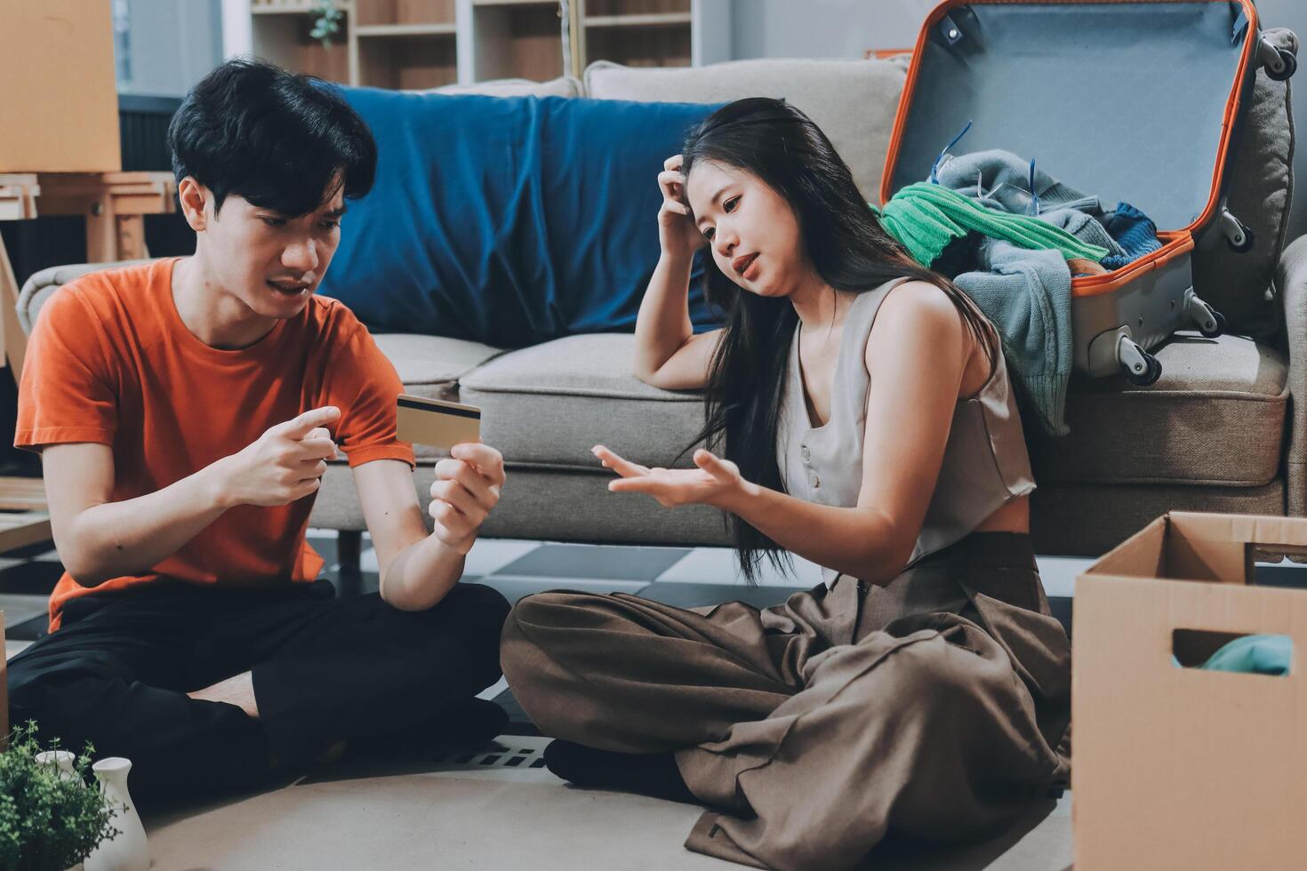 A man and woman sitting on the floor with boxes and a suitcase photo