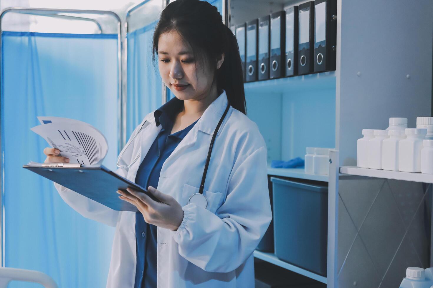 A female doctor is holding a clipboard while standing in front of a desk photo