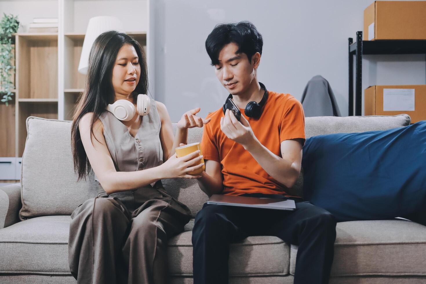 A young man and woman sitting on a couch with a box of food photo