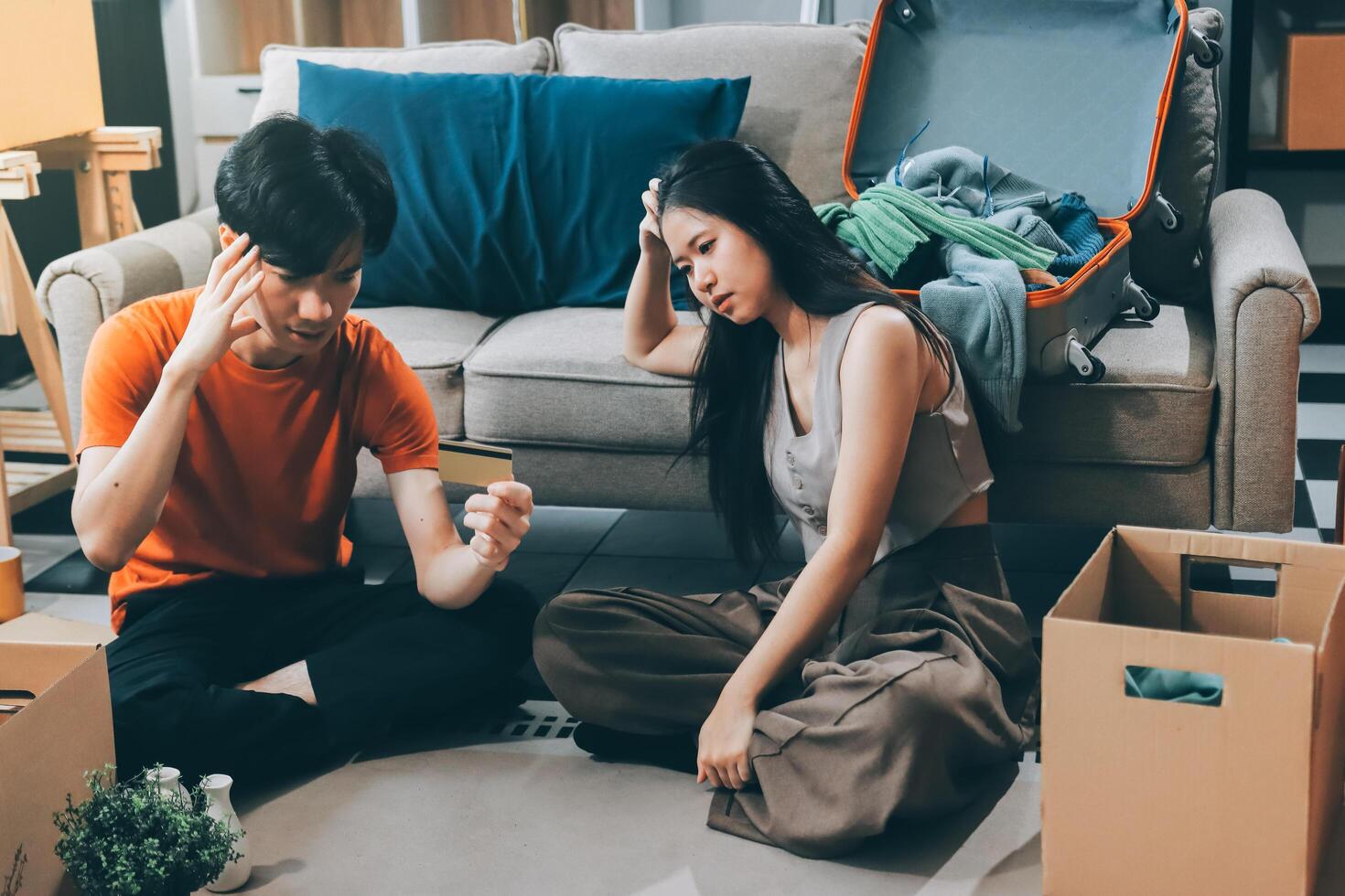 A man and woman sitting on the floor with boxes and a suitcase photo