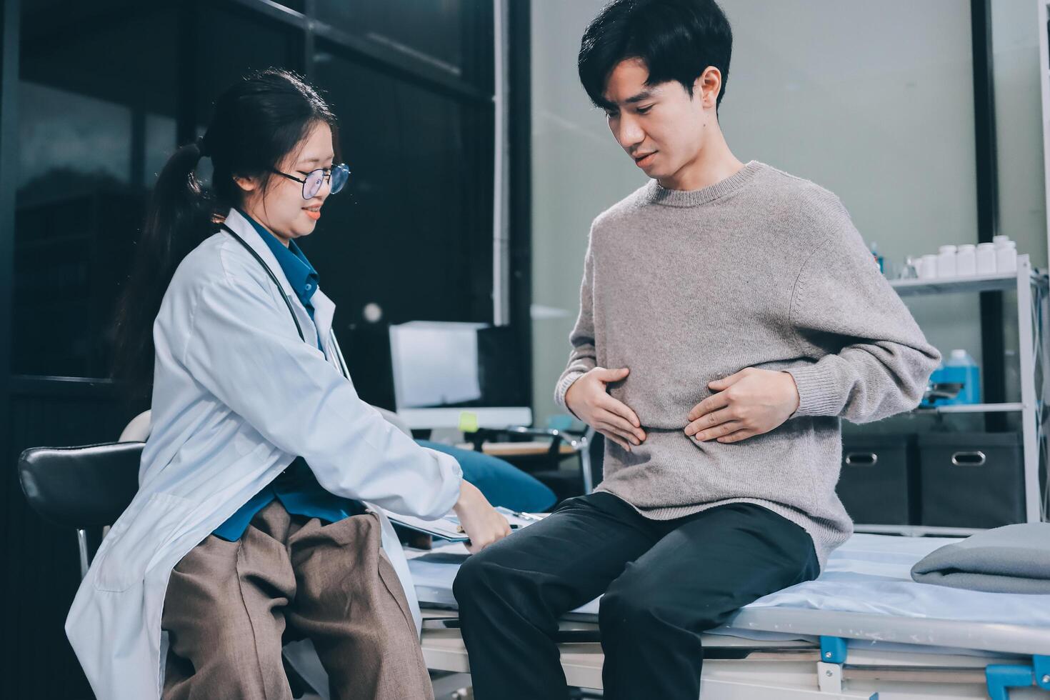 Asian doctor examining patient's stomach photo