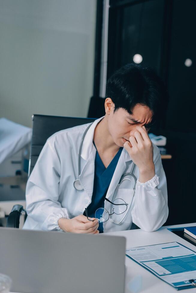 A doctor is sitting at his desk with his laptop photo