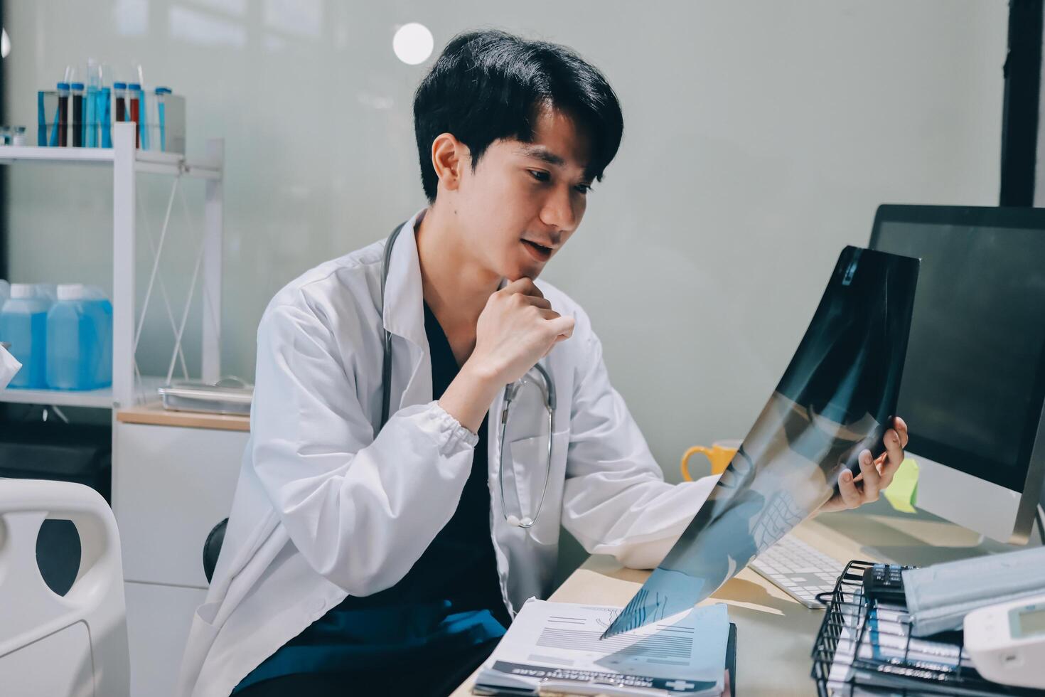 A man in a lab coat is looking at a x - ray photo