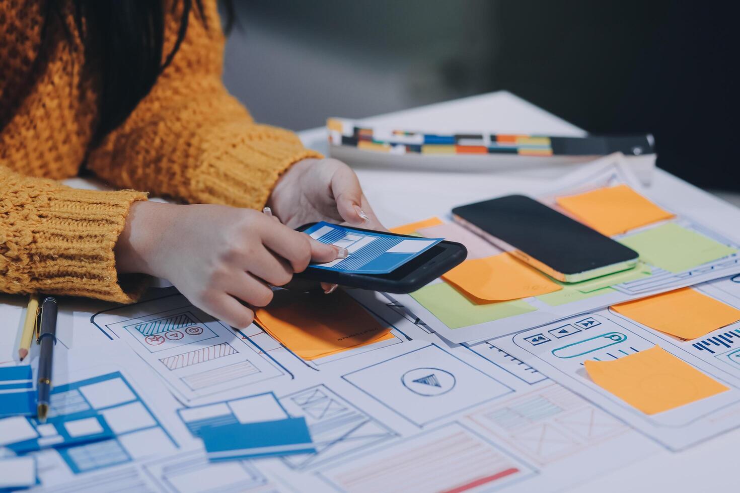 A woman using a smartphone to design a website photo