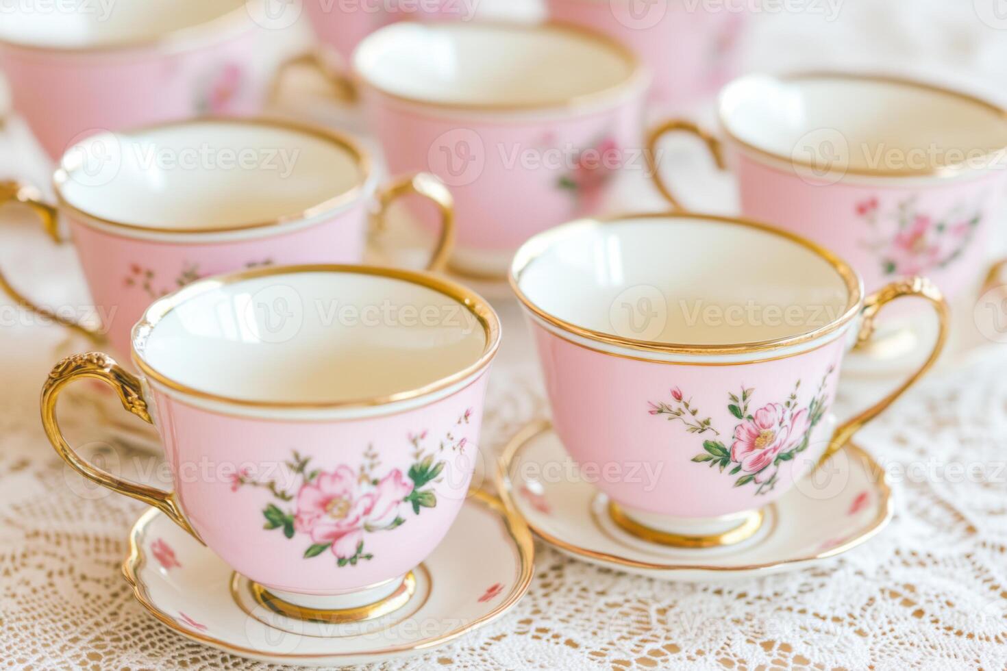 Vintage porcelain tea cups arranged elegantly on a lace tablecloth showcasing intricate floral designs in mocha brown and shell pink hues photo