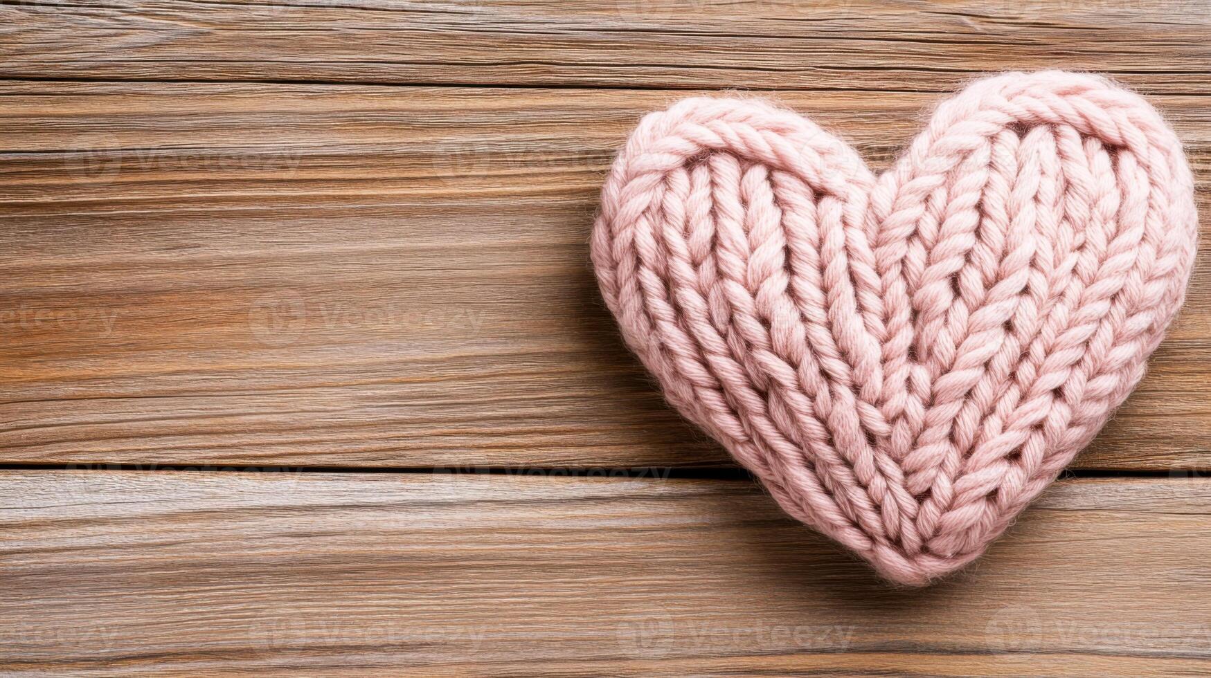 Soft pink knitted heart rests on rustic wooden surface, creating a cozy handmade atmosphere with gentle pastel tones photo