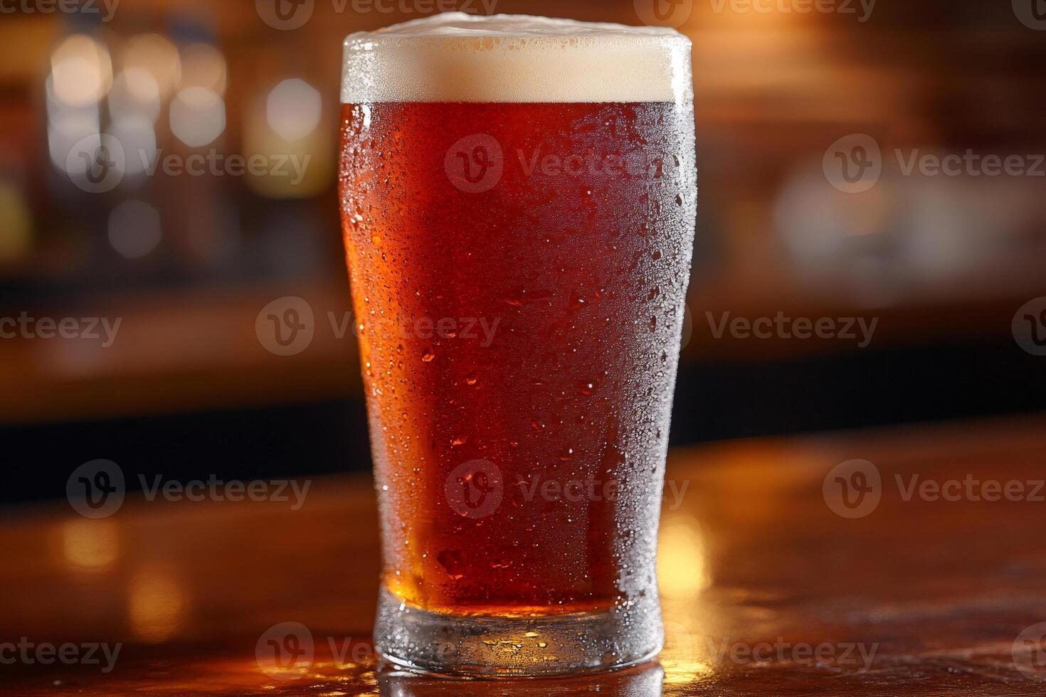Cold glass of amber beer is standing on a wooden bar counter photo