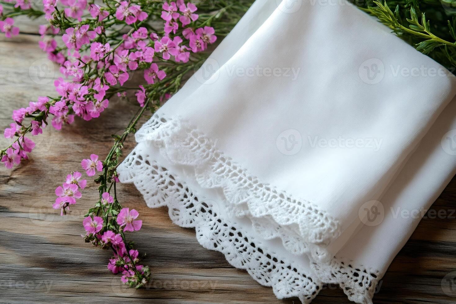 White lace handkerchiefs with pink flowers lying on wooden table photo