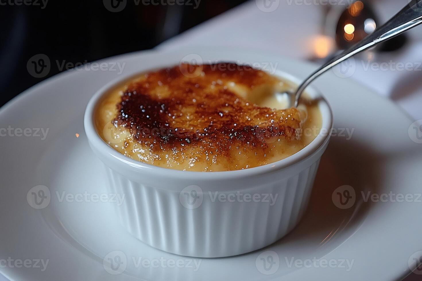 Spoon digging into a small bowl of creme brulee photo