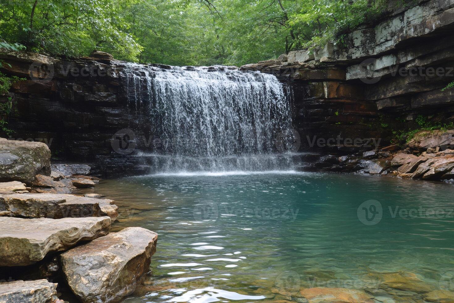 Waterfall cascading into rocky pool in lush forest photo