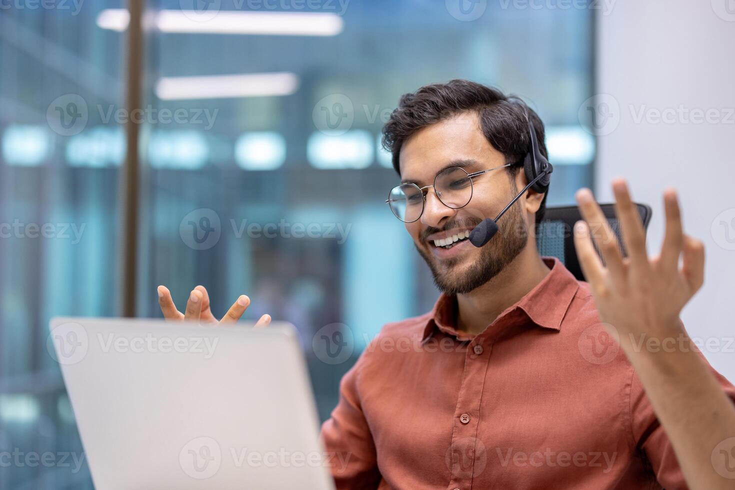 Latin American man businessman in online meeting using laptop and headset at office desk. Expressing enthusiasm during remote work call, technology connection, communication, engagement. photo