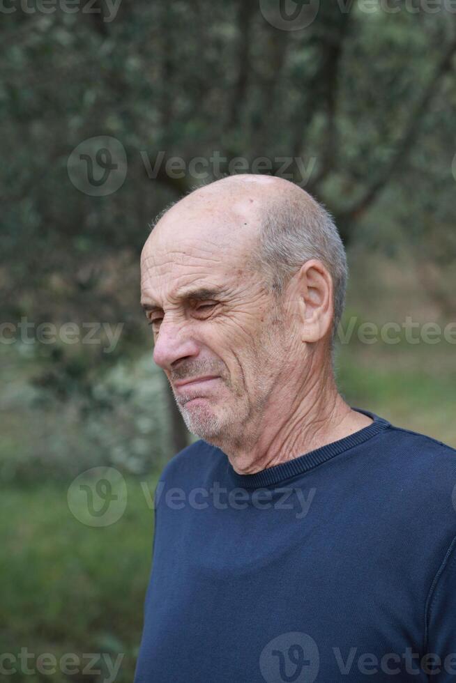 Elderly Bald Man Makes a Gross Face After Eating Bad Food In Nature photo