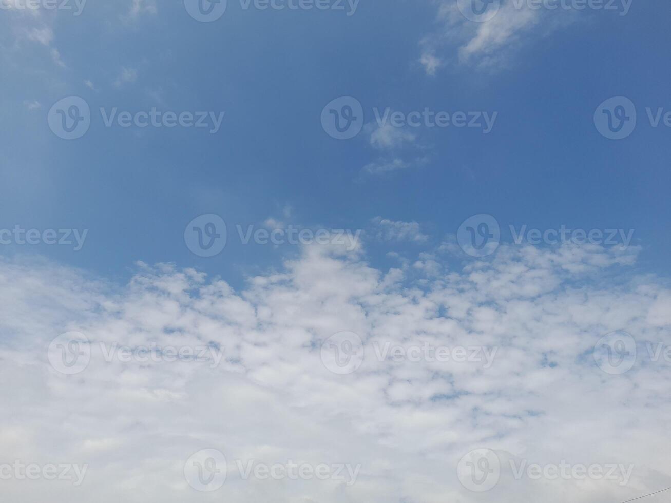 A vast expanse of clear blue sky with a few wispy clouds dotting the horizon photo