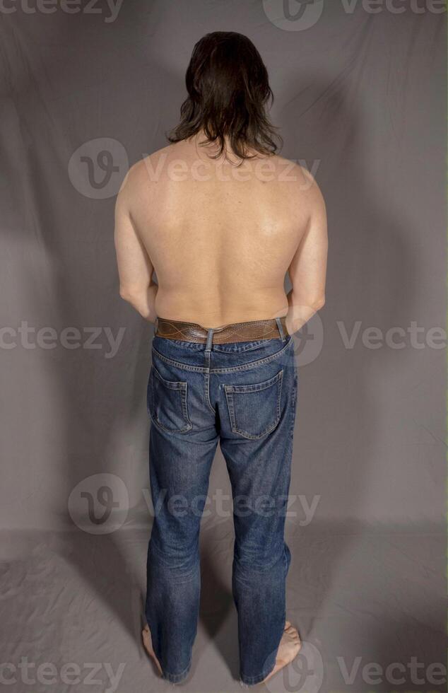 Muscular man back stay on a grey background photo