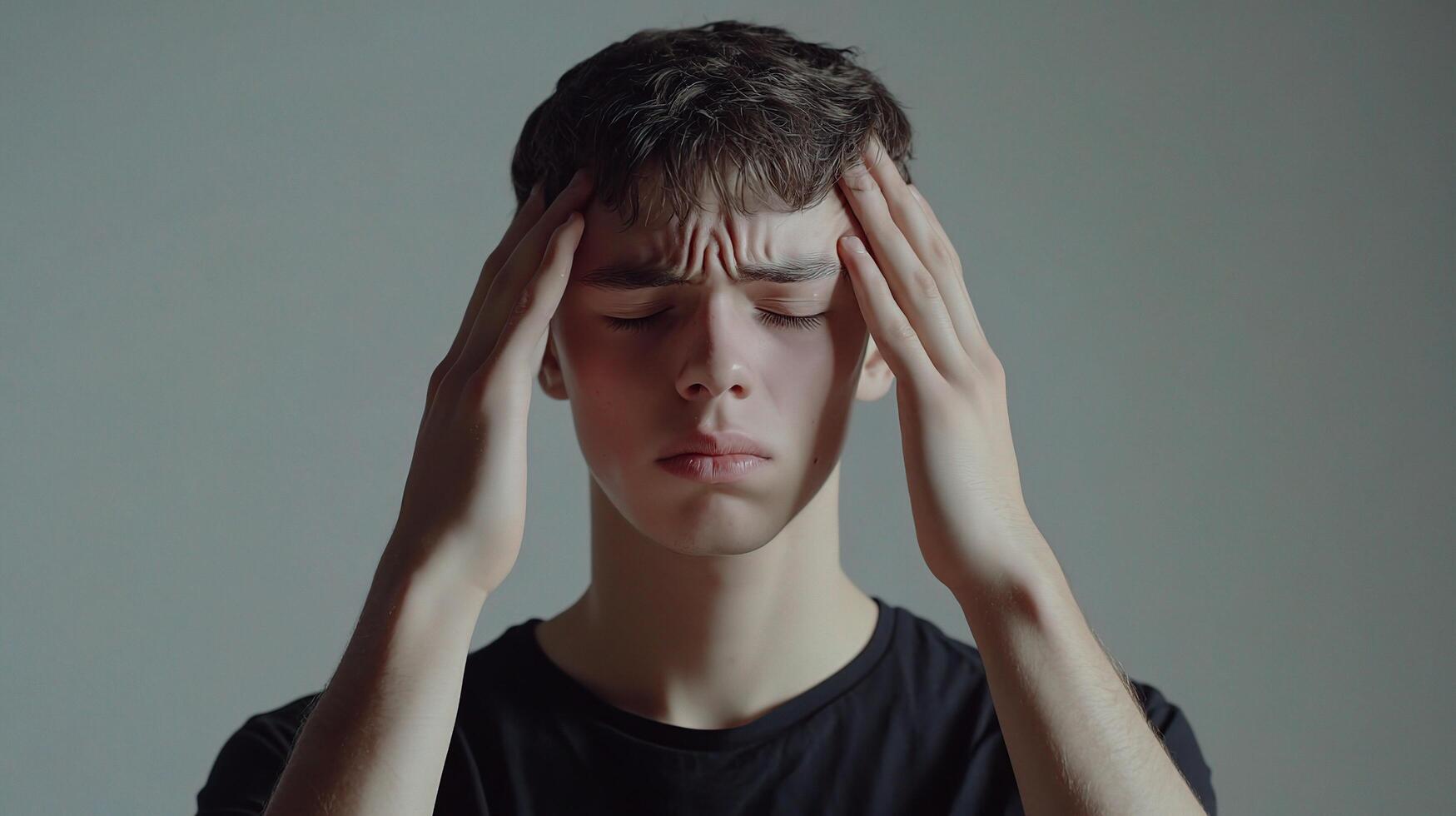 A young man is holding his head in pain photo