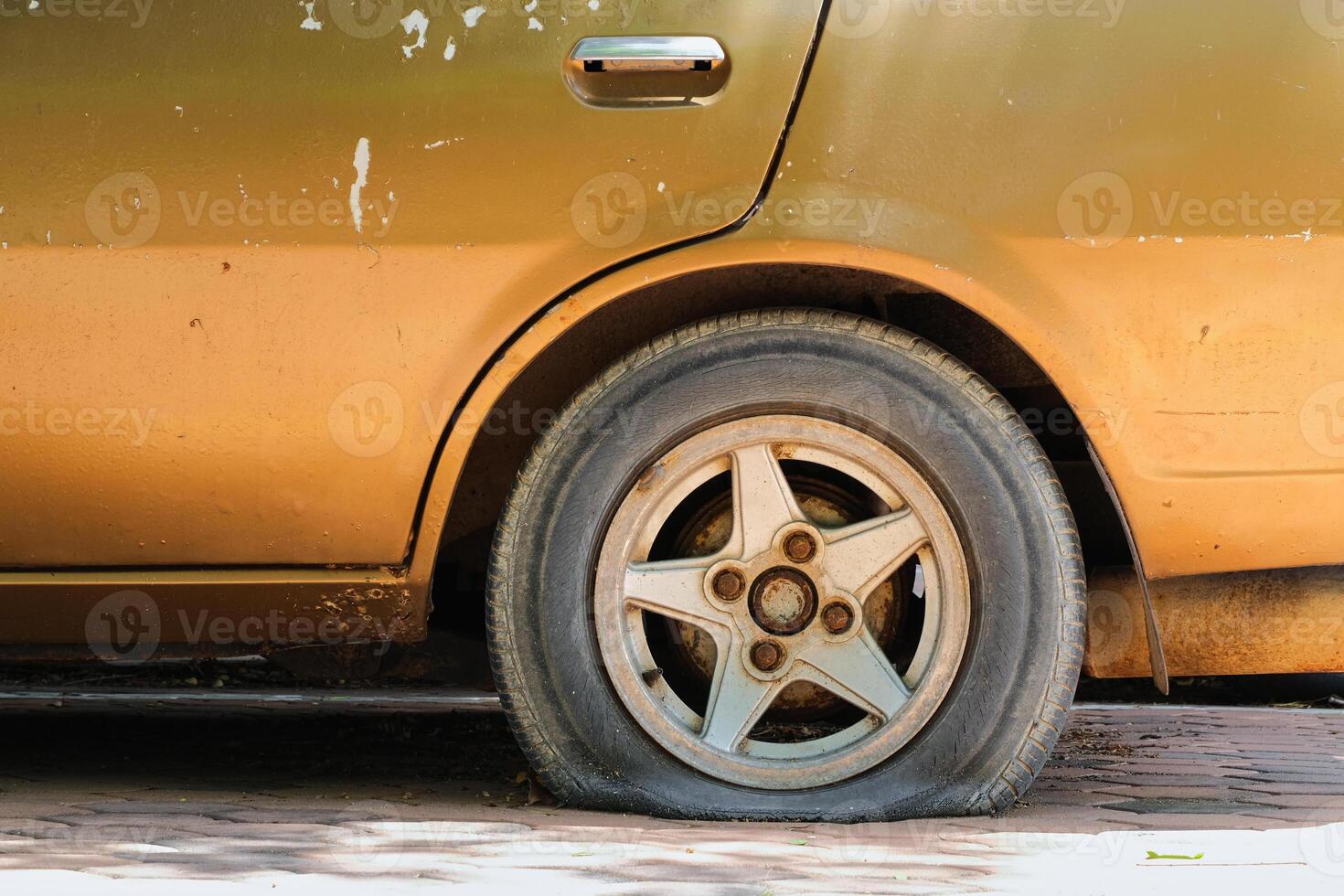 Gold car old, flat tire with rusty alloy wheel photo