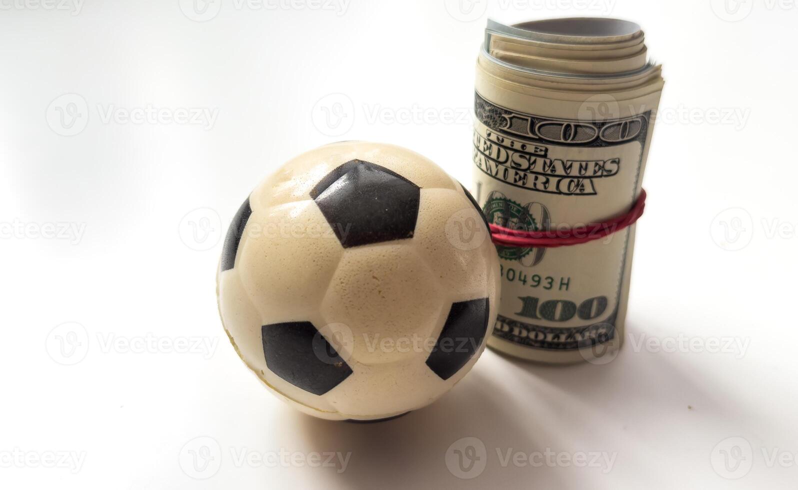 Little soccer ball with a roll of dollars lays photo