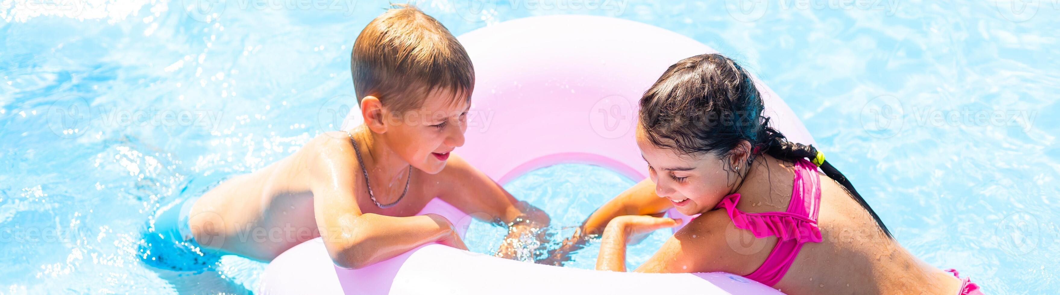 Child in swimming pool floating on toy ring. Kids swim. Colorful rainbow float for young kids. Little boy having fun on family summer vacation in tropical resort. Beach and water toys. Sun protection. photo
