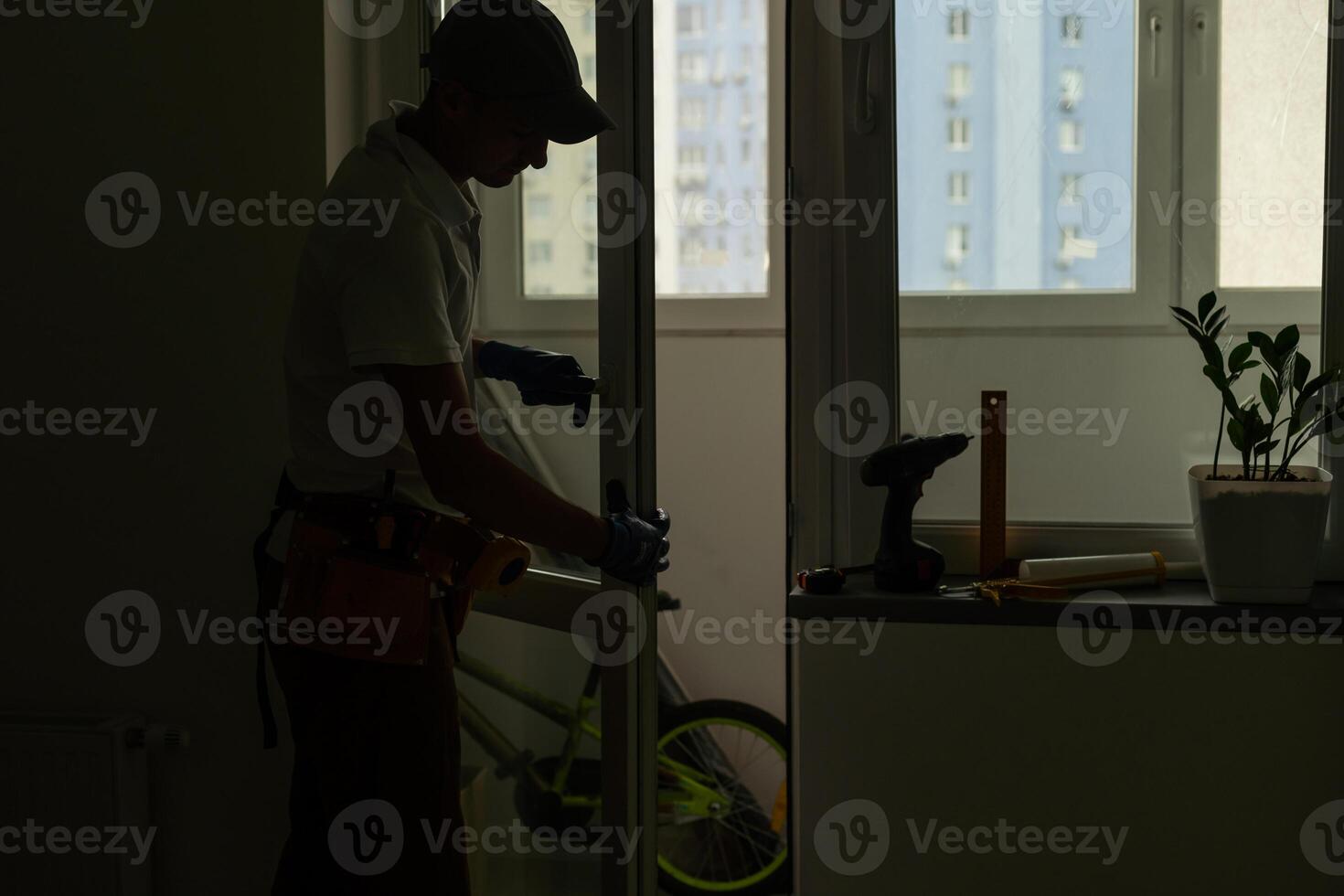 Master in gloves adjusting pvc windows with screwdriver closeup. Installation of plastic windows repair and maintenance concept. photo