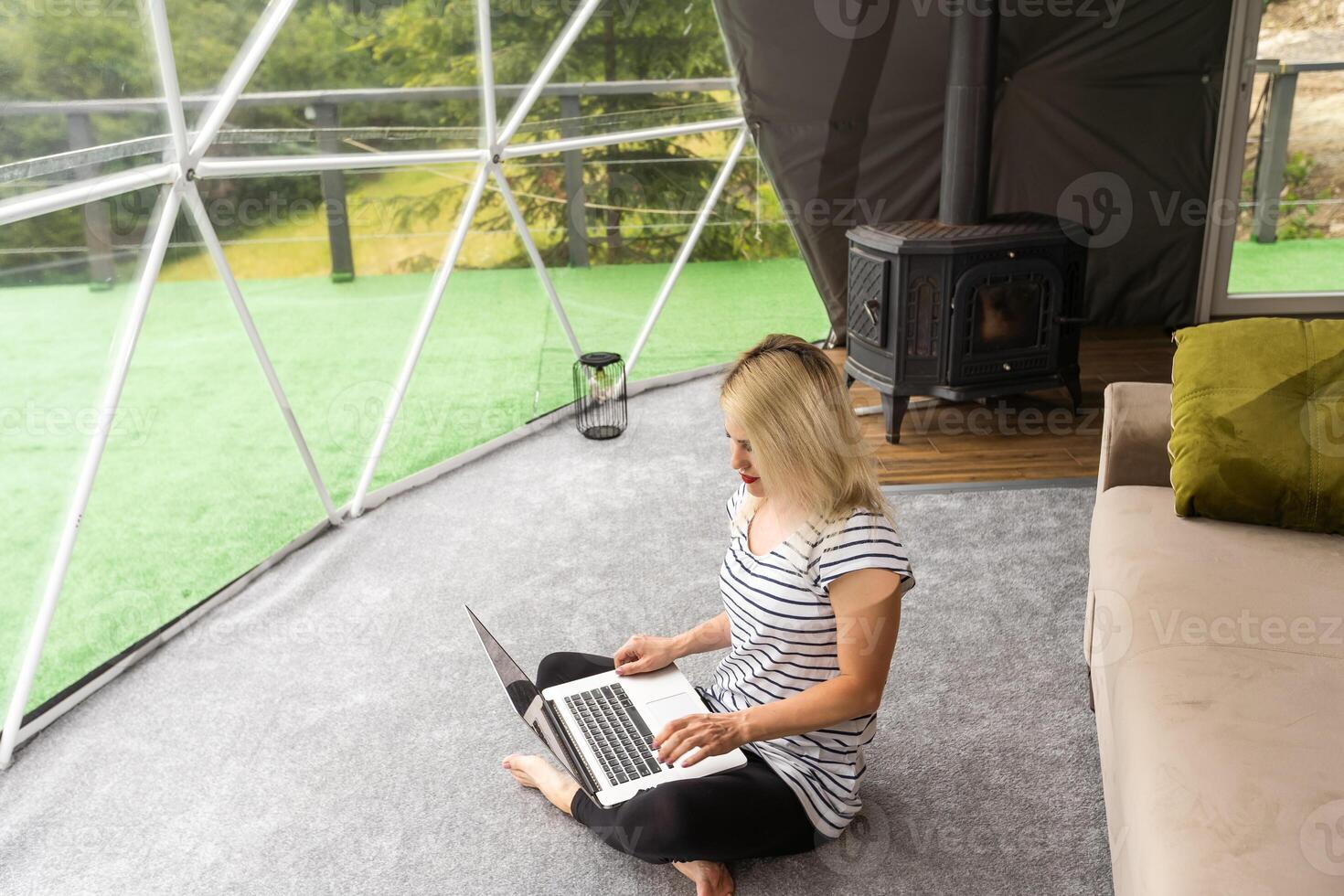 Transparent bubble tent at glamping, Lush forest around and interior. Woman with laptop photo