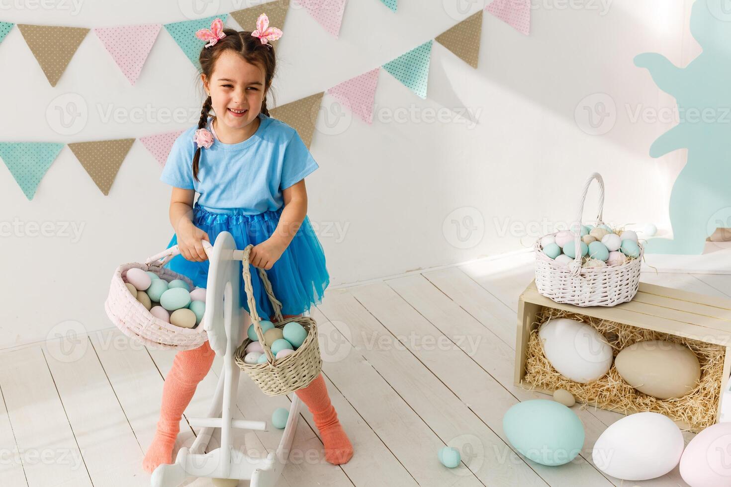 Getting ready to Easter. Lovely little girl holding an Easter egg and smiling with decoration in the background photo