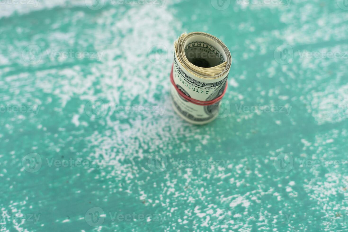 100 dollar bills twisted into tube and tied with an elastic band. white background, copy space for your text photo