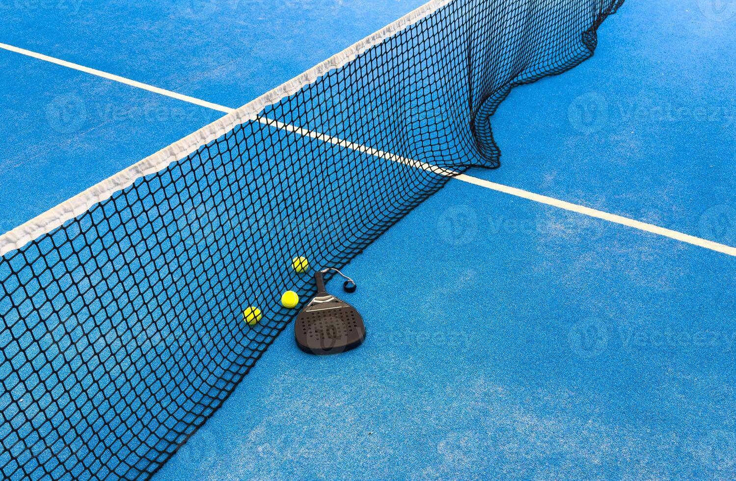 balls near the net of a blue paddle tennis court, sports courts photo