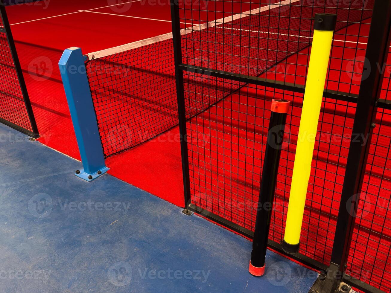 View of the net and the centre line of a red paddle tennis court. Racket sports photo