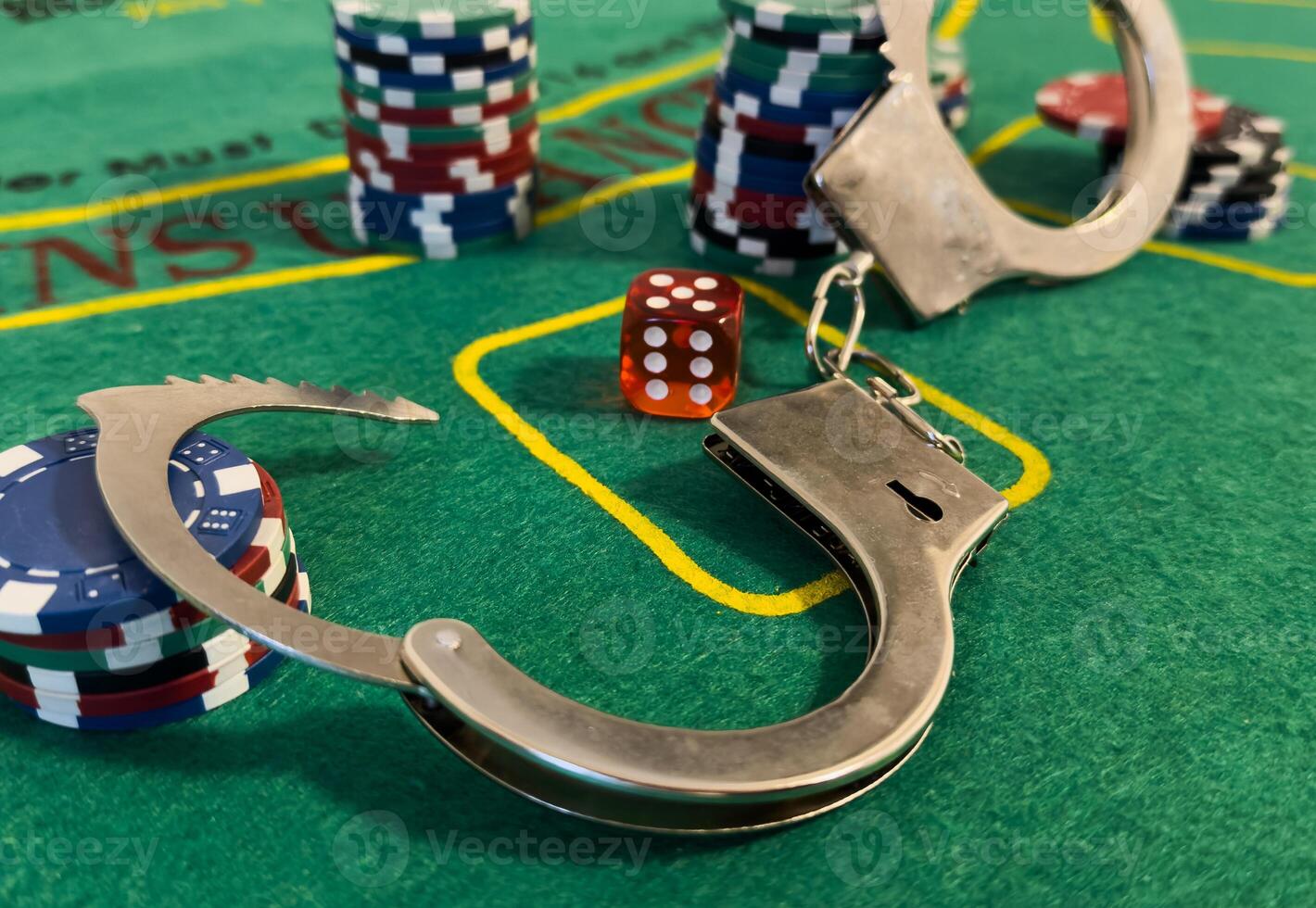 Handcuffs placed beside poker chips on a table at a dimly lit gambling setting photo