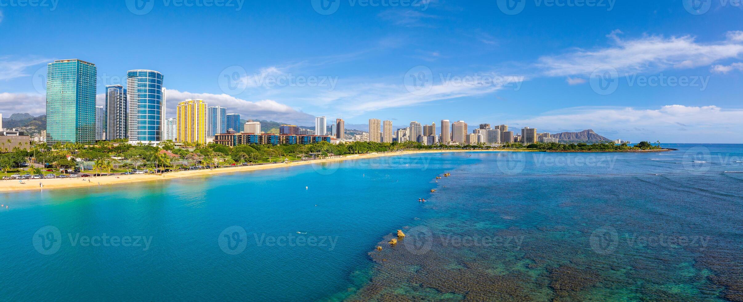Aerial view of Waikiki Beach in Honolulu, Hawaii, with turquoise waters, coral reefs, high rise buildings, and Diamond Head crater in the background. photo