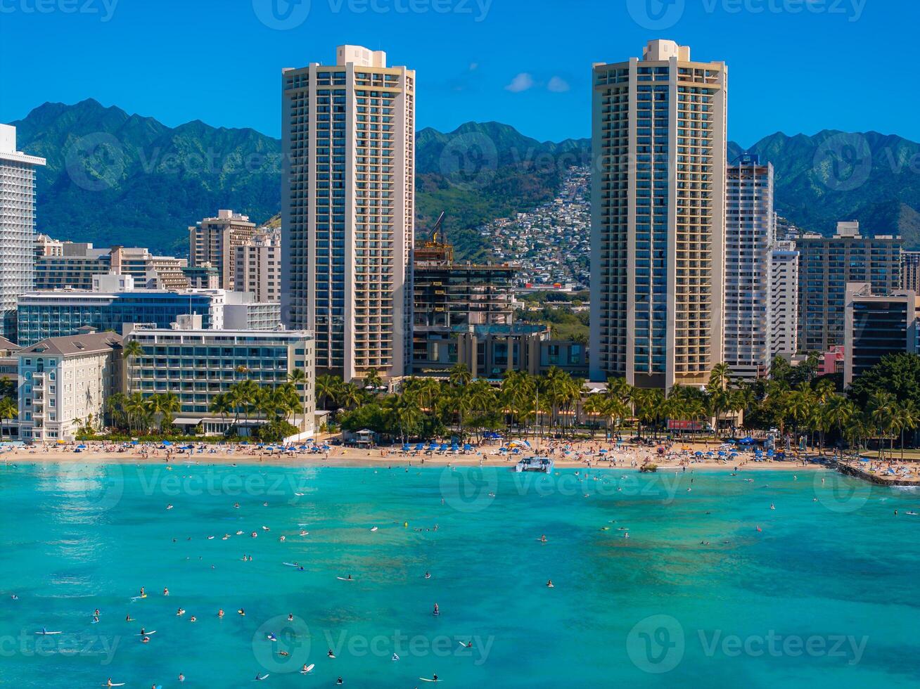 Aerial view of Waikiki Beach with turquoise waters, palm lined sandy shores, high rise buildings, and green mountains in Honolulu, Oahu, Hawaii. photo