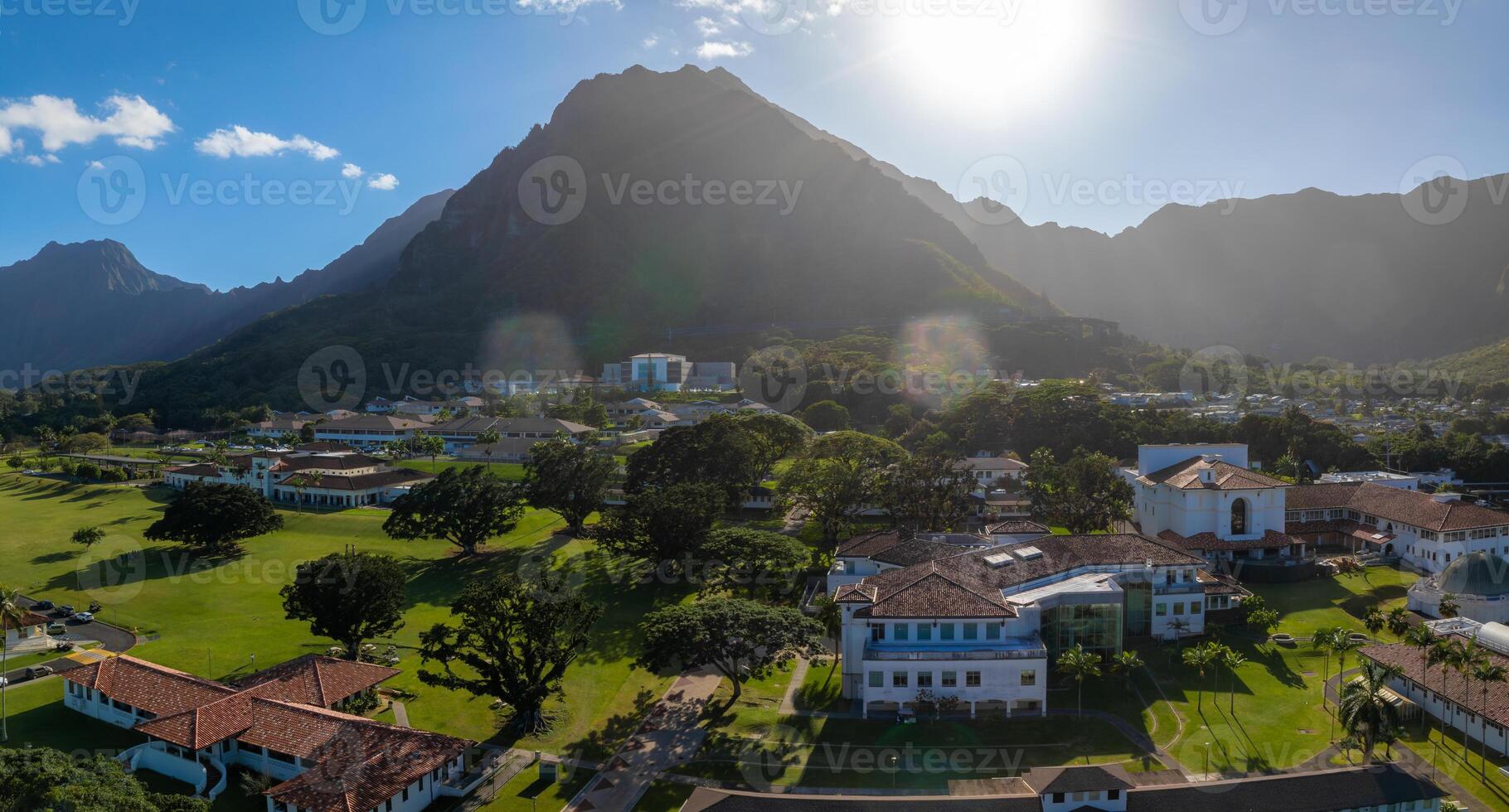 Aerial view of a green valley on Oahu Island, Hawaii, with the Ko olau mountain range, red roofed buildings, trees, and sunlight streaming over the scene. photo