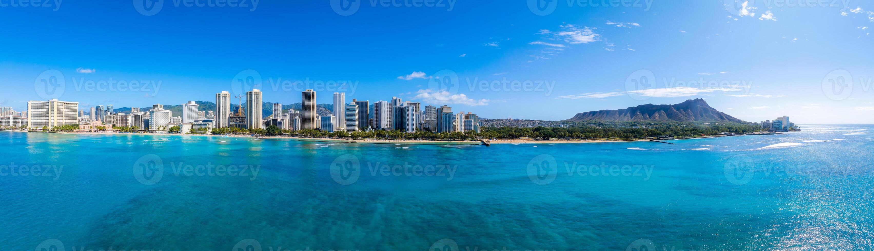 Aerial view of Honolulu, Hawaii, featuring Diamond Head crater, Waikiki Beach, turquoise waters, palm trees, and a modern cityscape under a clear sky. photo