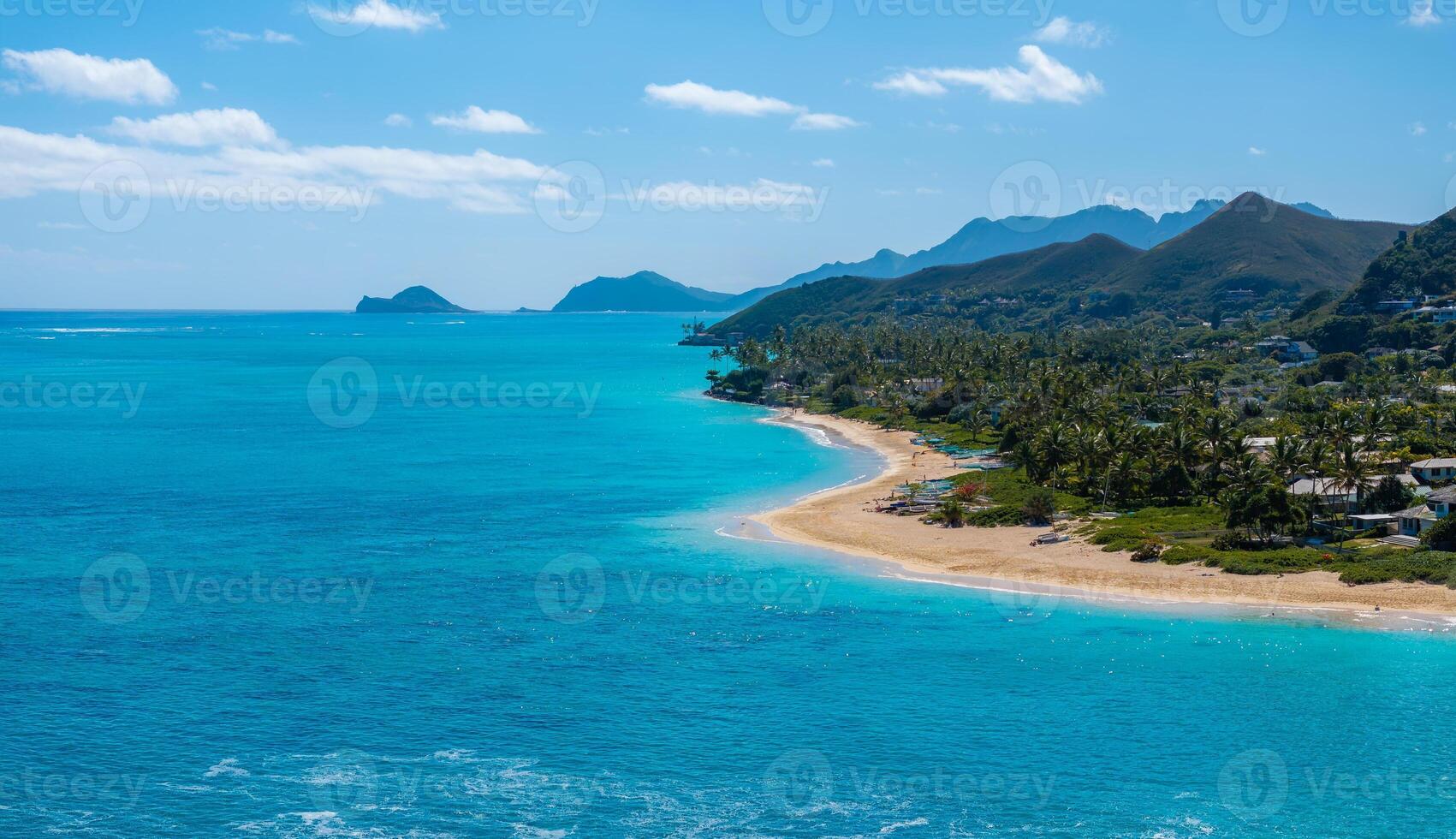 Tropical coastline on Oahu island, Hawaii, featuring turquoise waters, golden sandy Laniakai beach, lush greenery, rugged mountains, and small offshore islands. photo