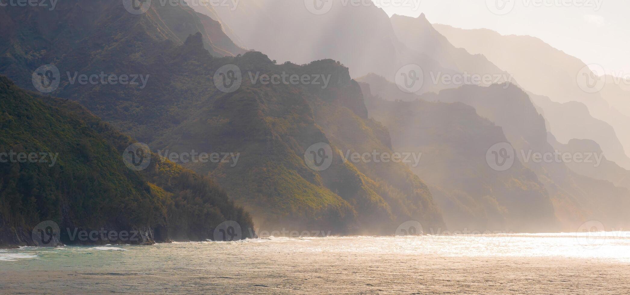The Napali Coast on Kauai Island, Hawaii, features rugged cliffs, lush greenery, and jagged peaks descending into the ocean under soft sunlight. photo