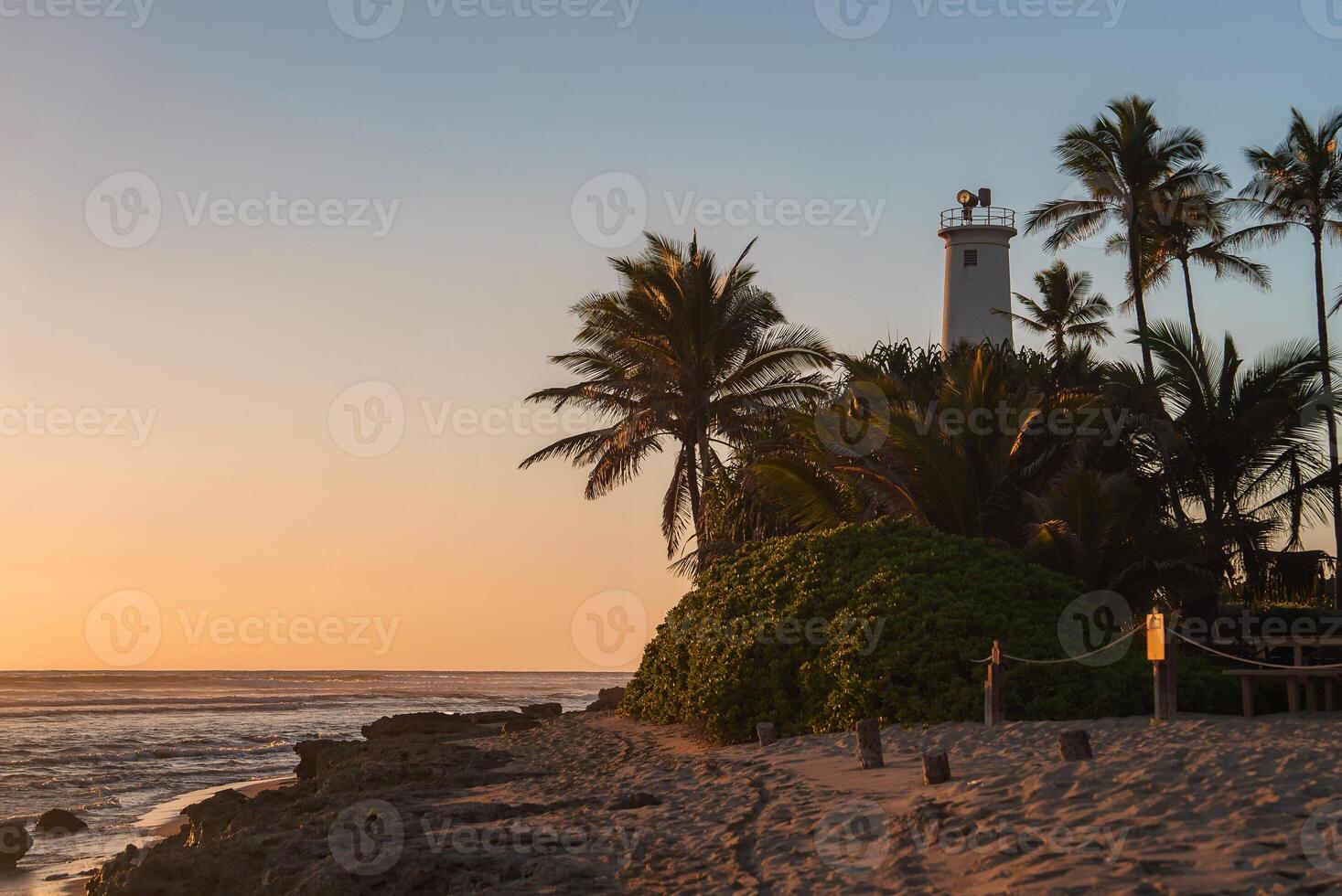 Sunset Beach Scene with Lighthouse and Palm Trees in Hawaii photo