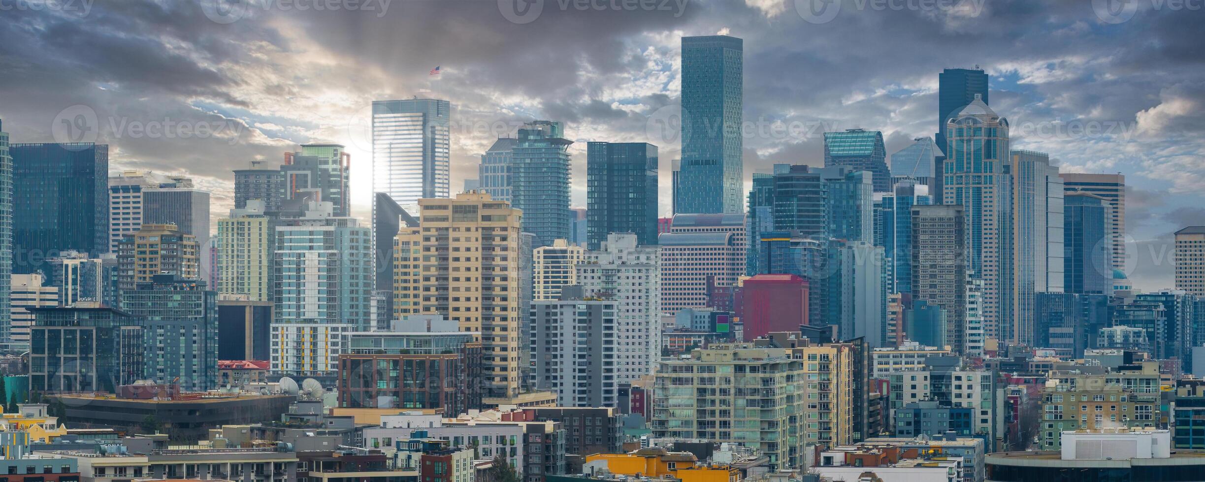 Aerial view of Seattle's downtown skyline featuring Columbia Center, modern skyscrapers, urban areas, and dramatic cloud formations in the sky. photo