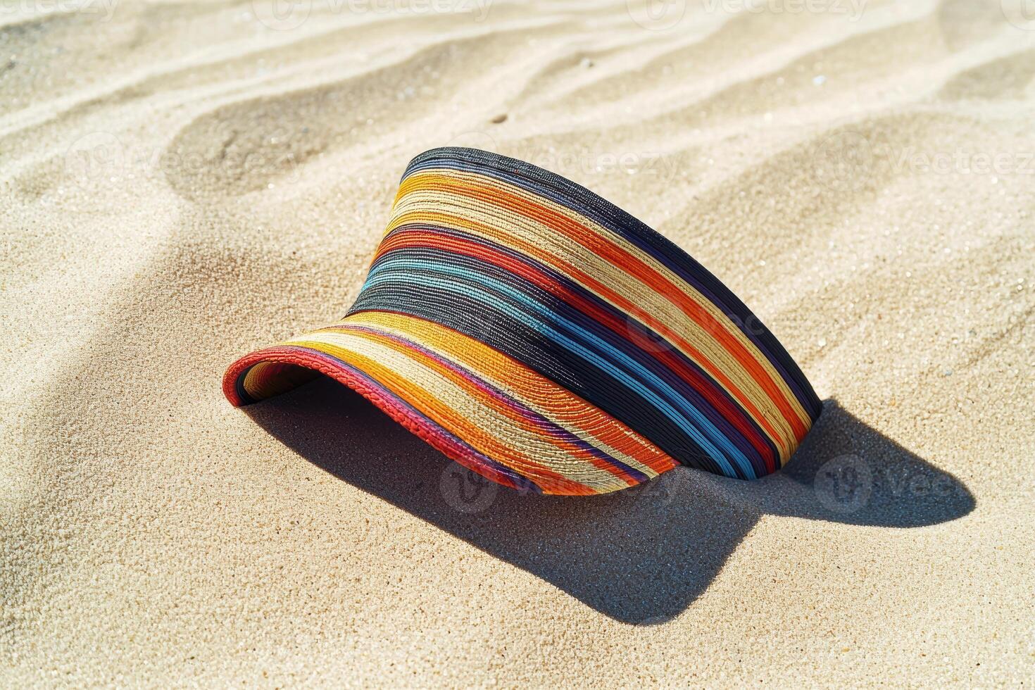 Vibrant multicolored sun hat resting on sandy beach surface photo